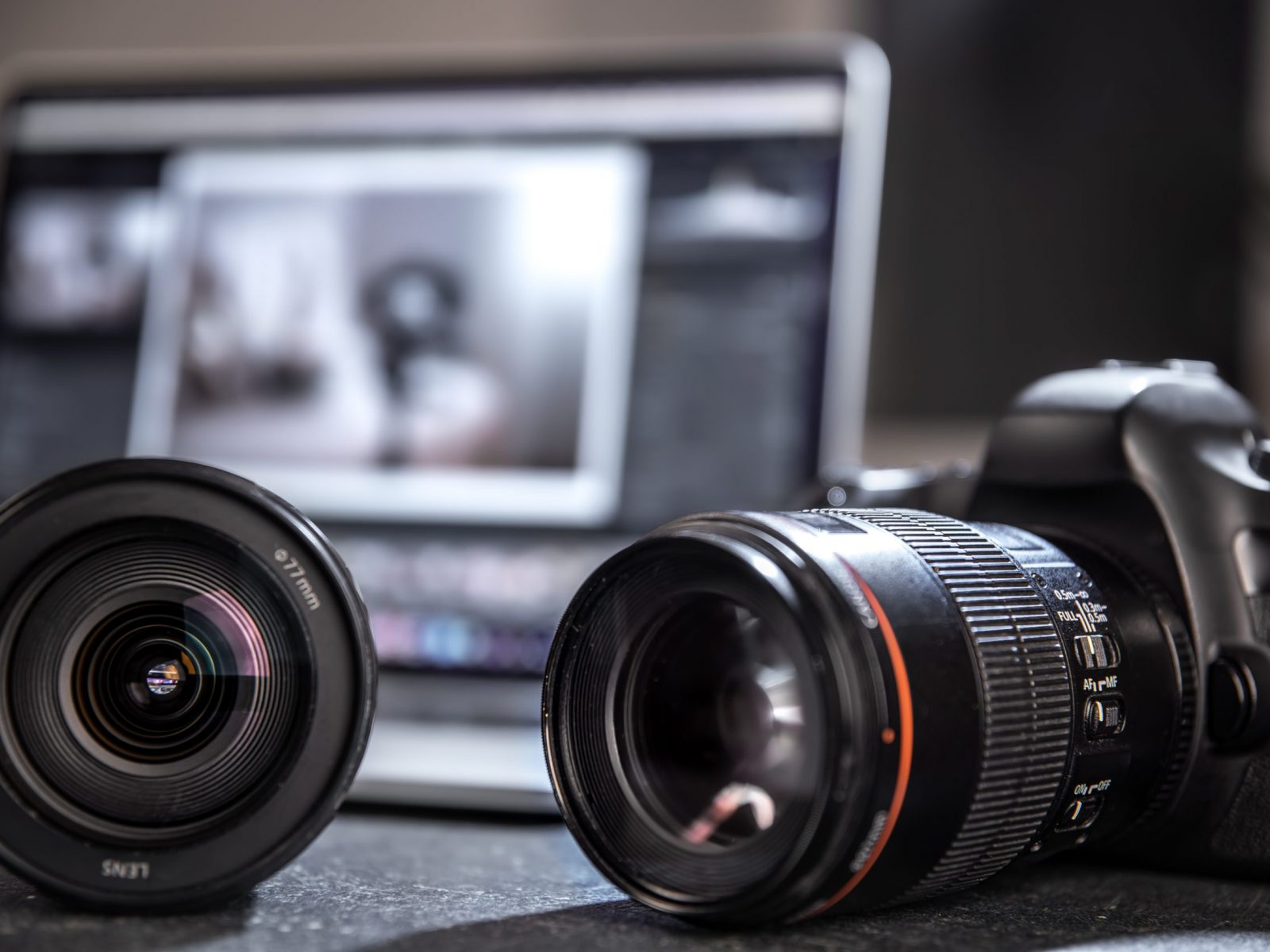 Professional camera and lens close-up on a photographer's desktop on a blurred background. The concept of professional equipment for photo and video.