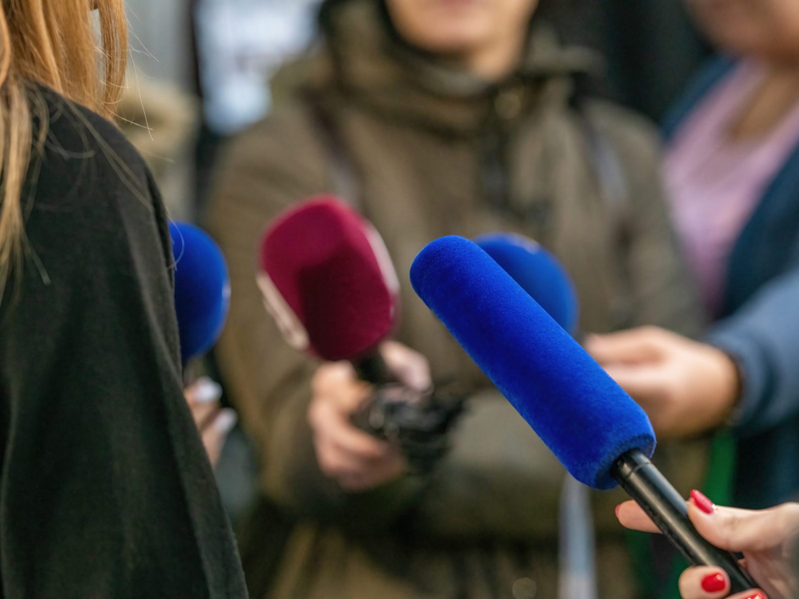 Journalists descends upon an event interview,with collective focus on interviewed person.